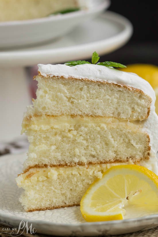 a tender white cake filled with tart lemon curd and covered with a fluffy whipped cream frosting - Lemon Cake Lemon Cake on a saucer.