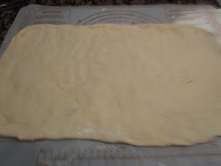 freshly made cinnamon roll dough on a pastry mat.