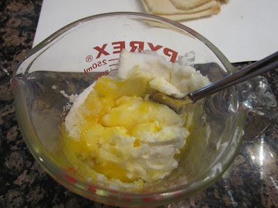 Stirring cream cheese filling in a glass measuring cup for cream cheese roll ups