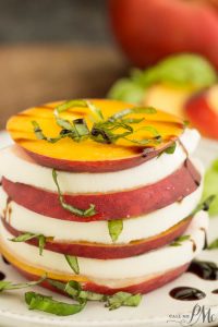 Savor the Peach Caprese Salad with stacked slices of peaches and mozzarella, garnished with basil and drizzled with a luscious balsamic reduction.
