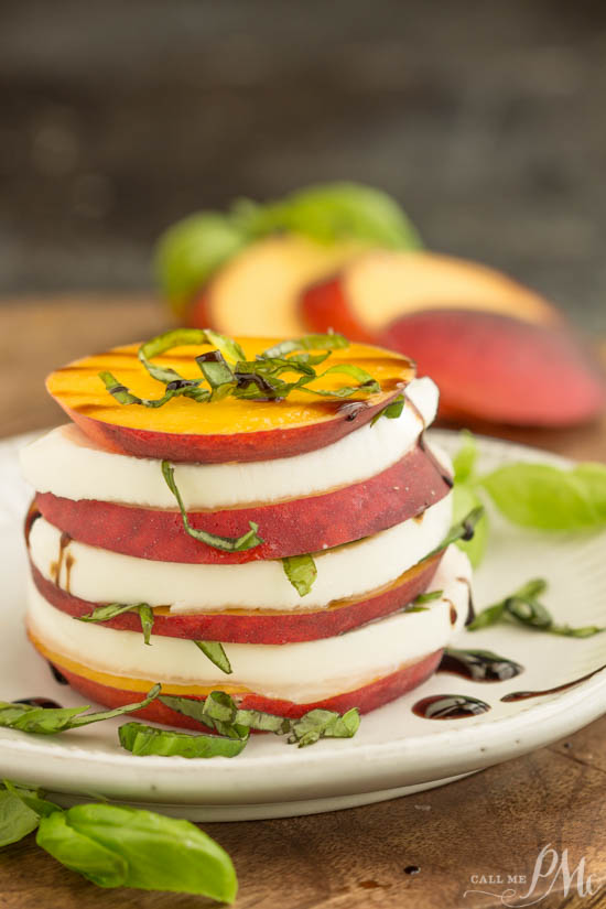 Enjoy a refreshing starter, featuring stacked peach and mozzarella slices topped with basil, all drizzled elegantly on a white plate. In the background, extra peach slices and basil leaves enhance the presentation.