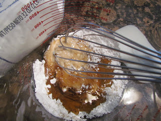 Bacon Breakfast Rolls with Maple Glaze confectioners sugar and syrup in a glass bowl.