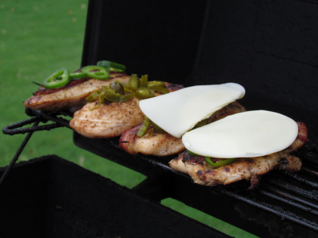 chicken on grill with bacon and jalapenos and cheese