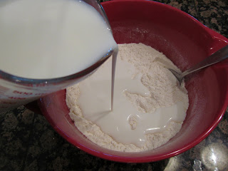 Pouring milk into a bowl with flour in it.