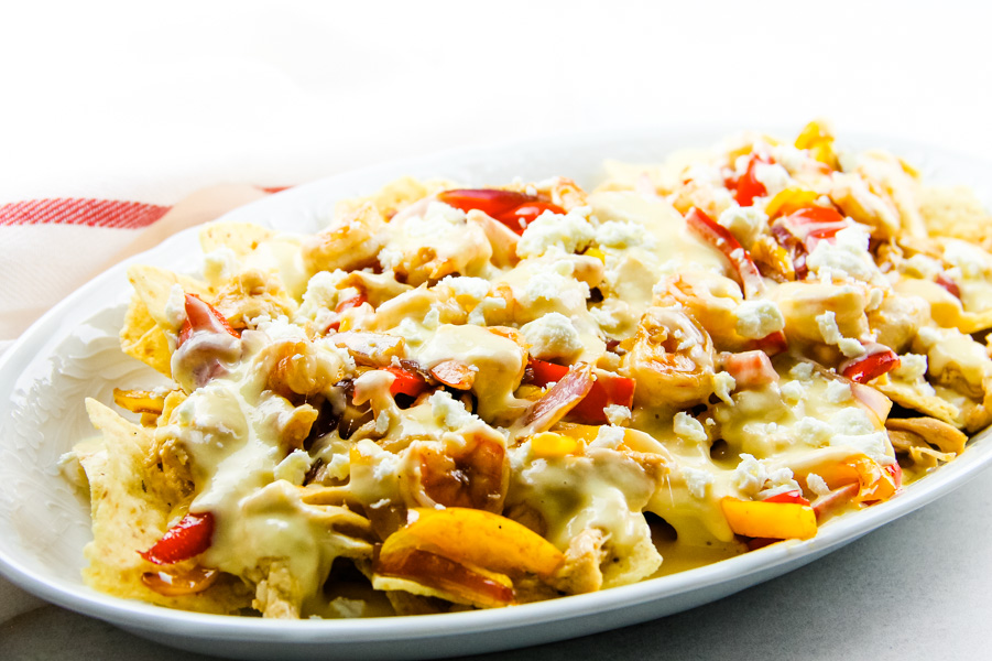 Chicken Shrimp Fajita Nachos are delicious when layered with all the good stuff chicken, shrimp, peppers, onions, and cheese. #chicken #shrimp #fajita #nachos white plate full of food