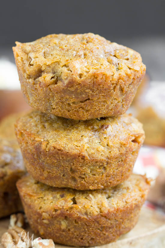 A stack of three golden-brown pecan pie muffins, with a slightly crumbly texture, placed on a wooden surface.