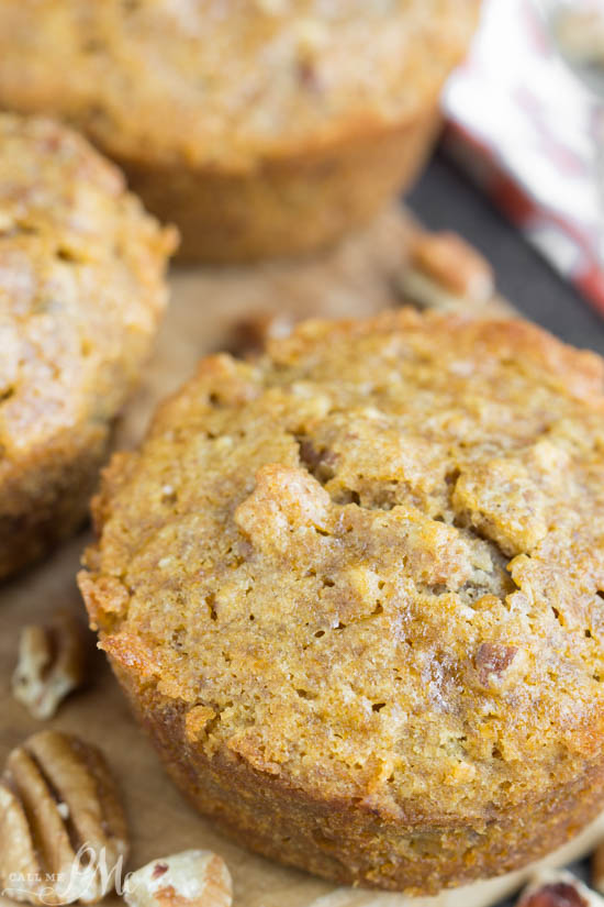 Close-up of a golden-brown pecan pie muffin with a crumbly texture, surrounded by pecan pieces.