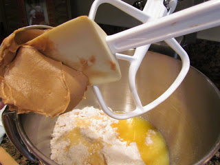 adding peanut butter to a mixing bowl with cake mix.