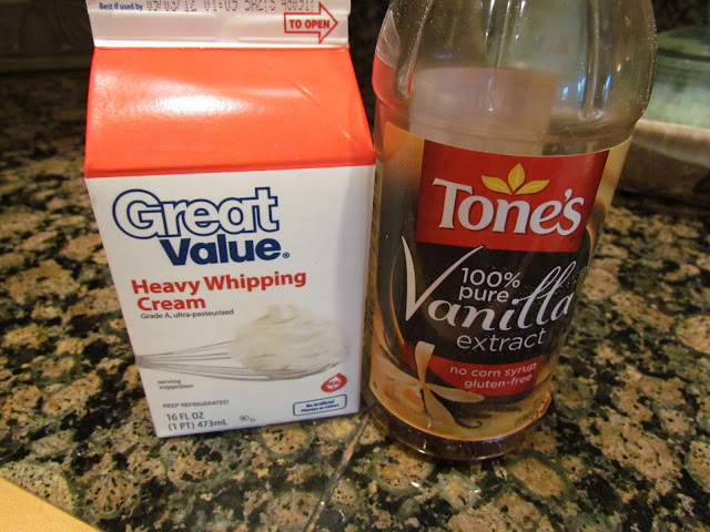 One pint of heavy whipping cream and a bottle of vanilla extract sitting on a kitchen counter.