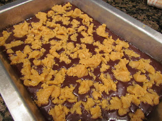 scoops of peanut butter on chocolate cake batter in a baking pan.