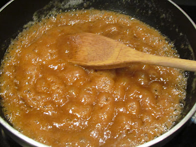 Caramel sauce bubbling in a skillet with a wood spoon.