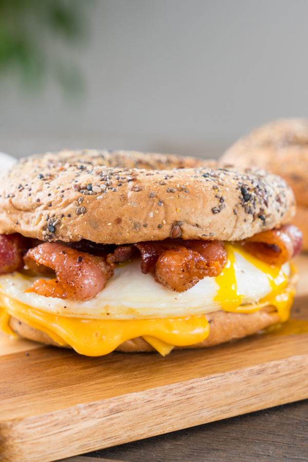 Bacon, egg and cheese breakfast sandwich with an everything bagel on cutting board