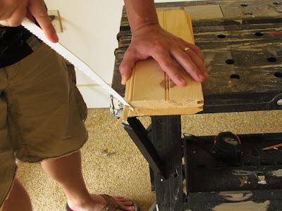 Man cutting piece of bead board with hand saw.