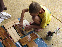 Boy staining pieces of wood.