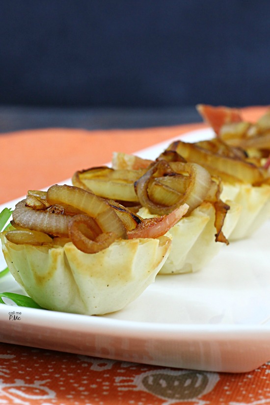 caramelized onions in phyllo cups on a white platter.