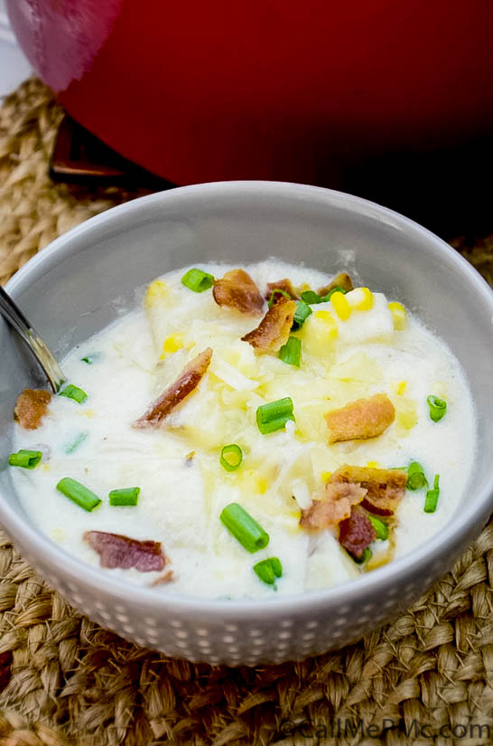 Corn and potato chowder with bacon and chives in a small white bowl.