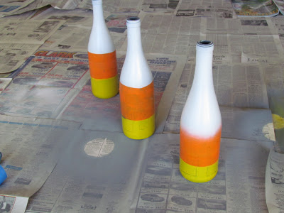 fall decorating project - three bottles painted in yellow, orange and white to look like candy corn.