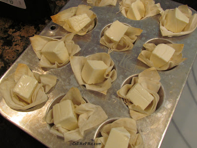 cubes of brie cheese in unbaked phyllo cups on a baking sheet.