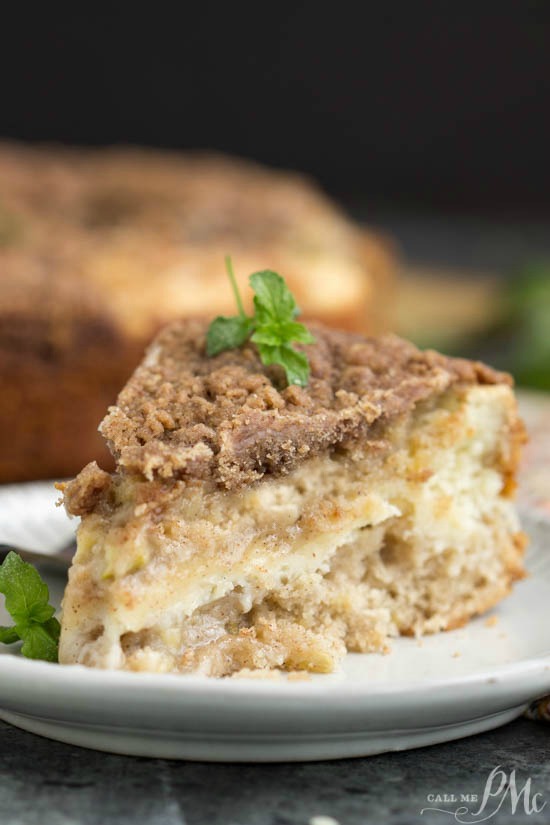 Apple Cinnamon Coffee Cake is a tender, spiced apple cake with a thread of cream cheese running through it and a nutty cinnamon pecan streusel sprinkled on top! slice of cake on plate