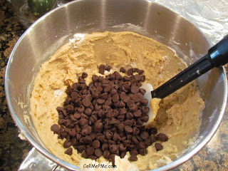 Stirring chocolate chips into a bowl of cookie dough.