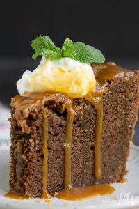 A slice of Irish Cream chocolate pound cake topped with whipped cream, caramel sauce, and a mint sprig graces the plate.