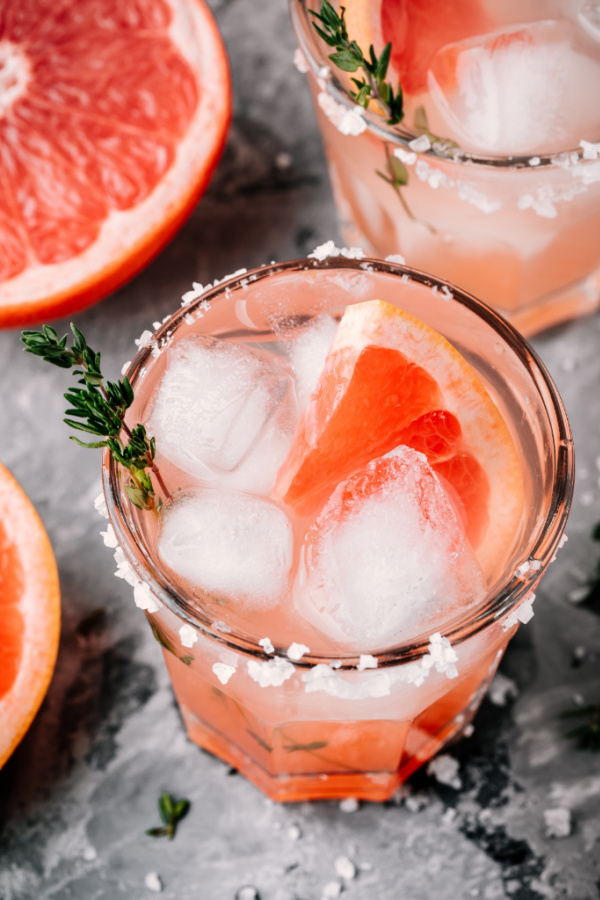 Grapefruit salty dog Cocktail with ice in glass on gray stone background Pink Salty Dog
