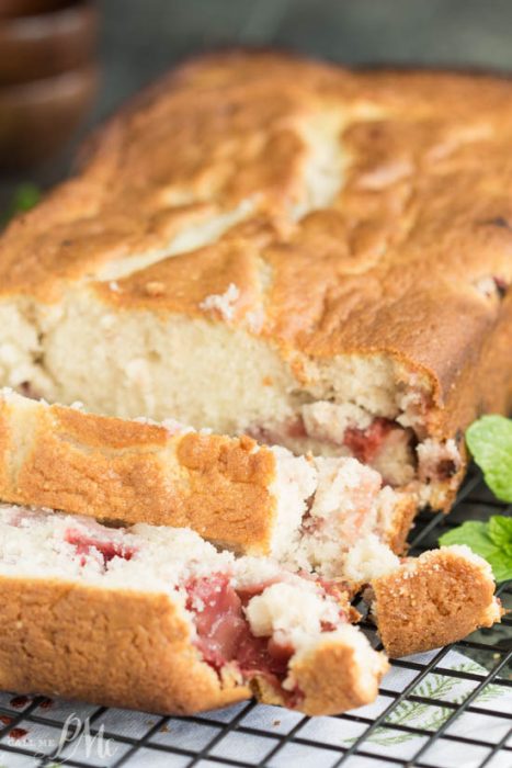 Strawberry Bread recipe A loaf of Easy Strawberry Bread with a golden crust is partially sliced, revealing its light, crumbly texture and sweet strawberry pieces inside.