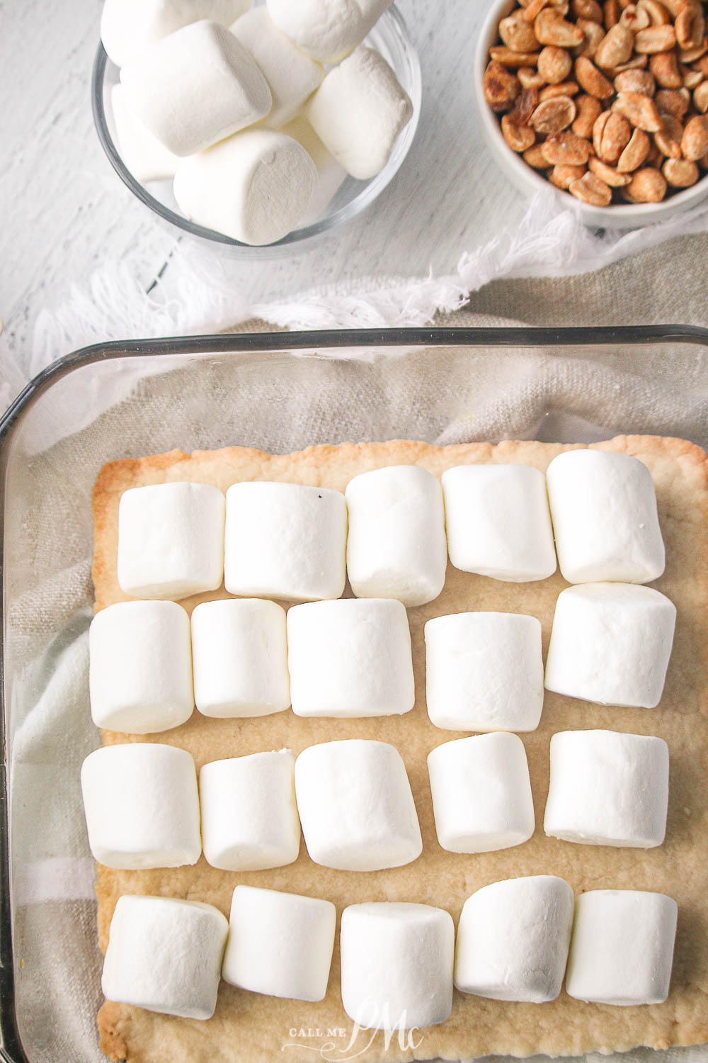 marshmallows lined up in a baking pan over dessert batter.