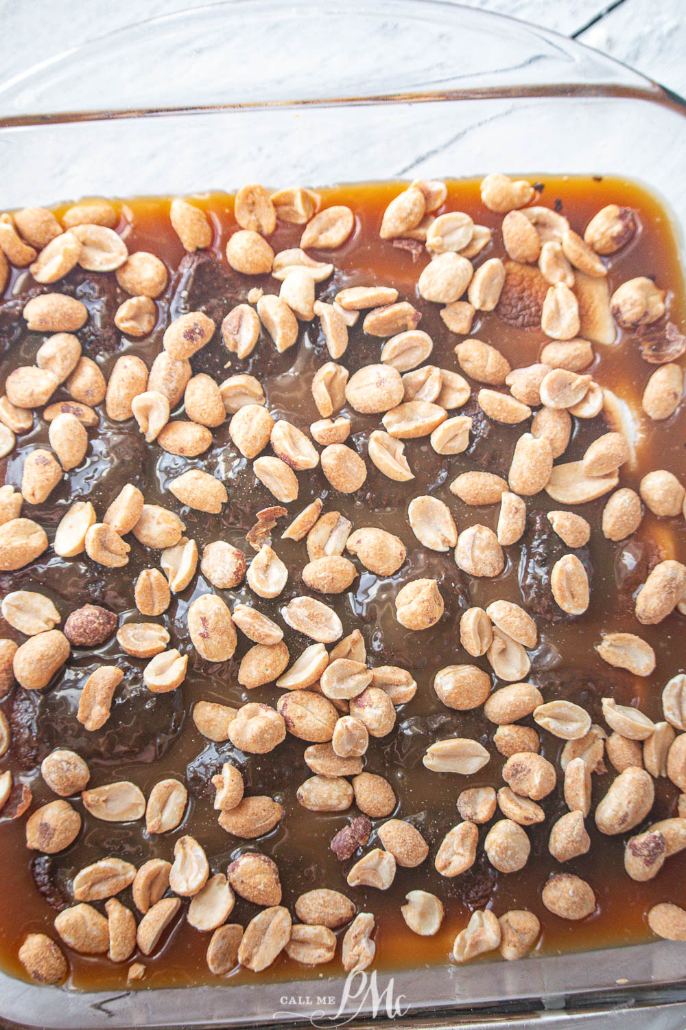 caramel and peanuts in a square glass baking dish.