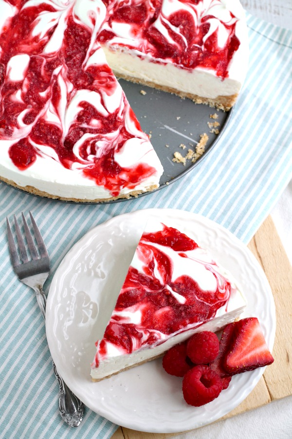 Quick and simple to prepare, Raspberry Strawberry No-Bake Cheesecake is an ideal dessert recipe for hot weather. #cheesecake #nobake #nocook #dessert #recipe #raspberry #strawberry Red and white dessert with one slice cut out on a saucer.