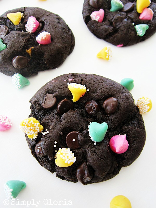 Triple Dark Chocolate Cookies - SimplyGloria.com A close-up of chocolate cookies from 50 Shades of Chocolate, topped with colorful candy pieces and sprinkles, arranged on a white surface.