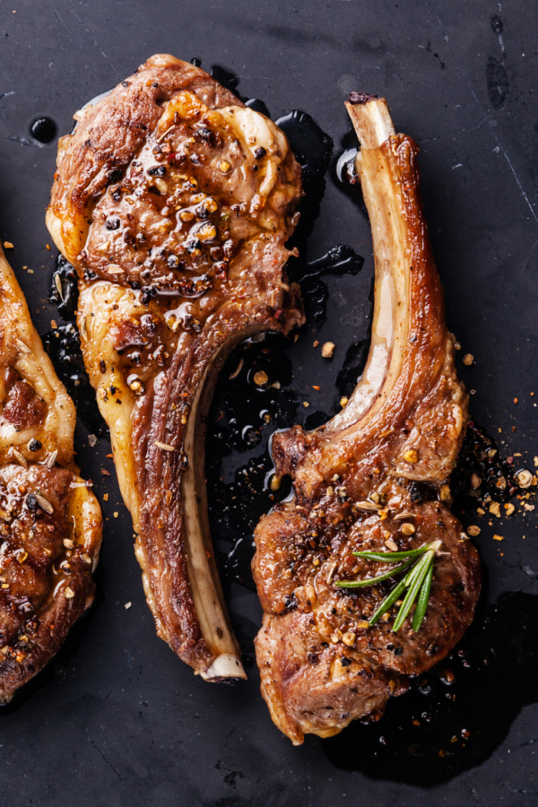 Roasted lamb ribs with spices on black marble background Grilled Lamb Lollipops are so easy to make and taste wonderful.ย They the perfect recipe for entertaining and the holidays!