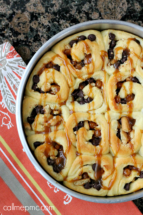 A pan of rolls with chocolate chips and caramel sauce.