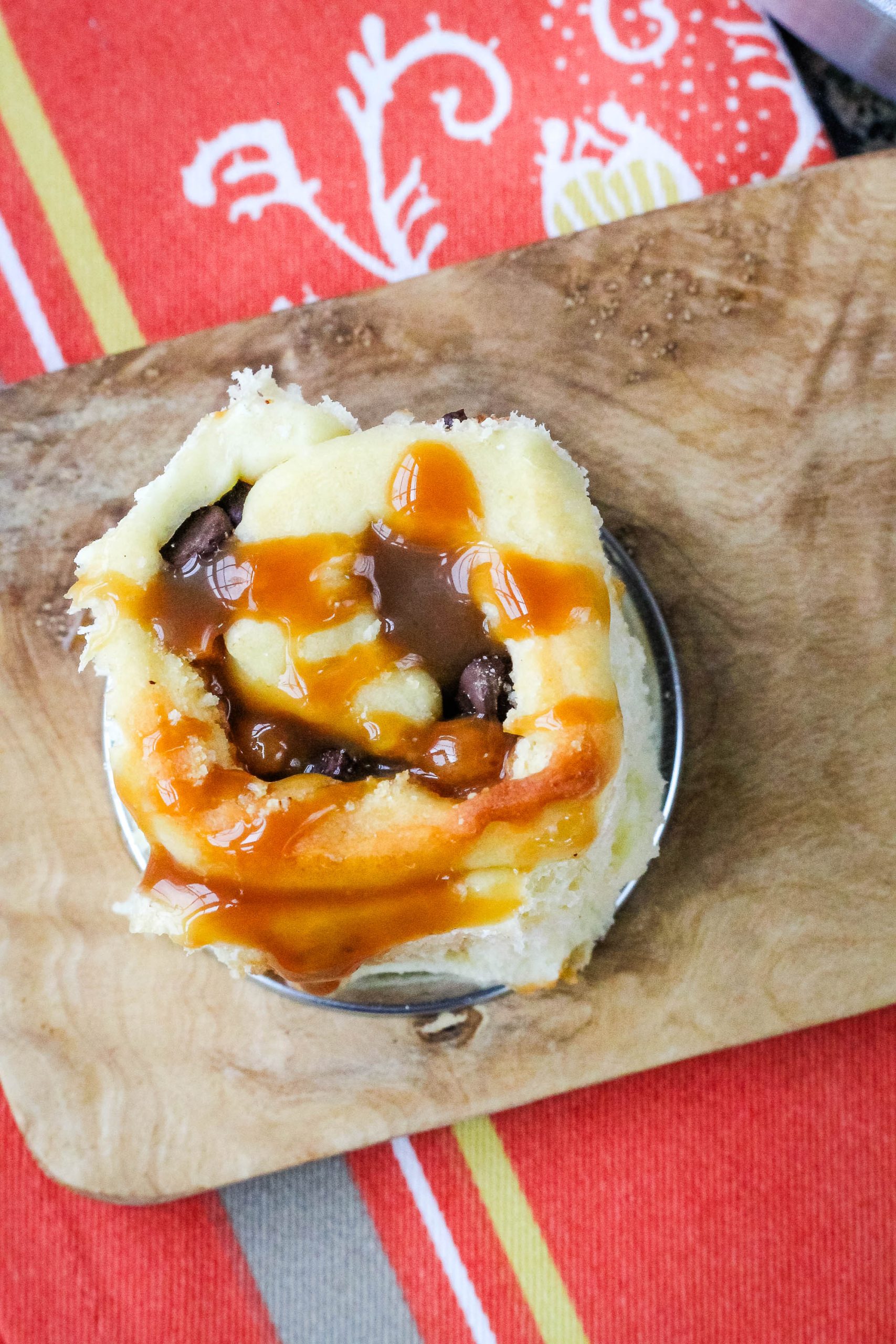 A sweet roll is sitting on a wooden cutting board.