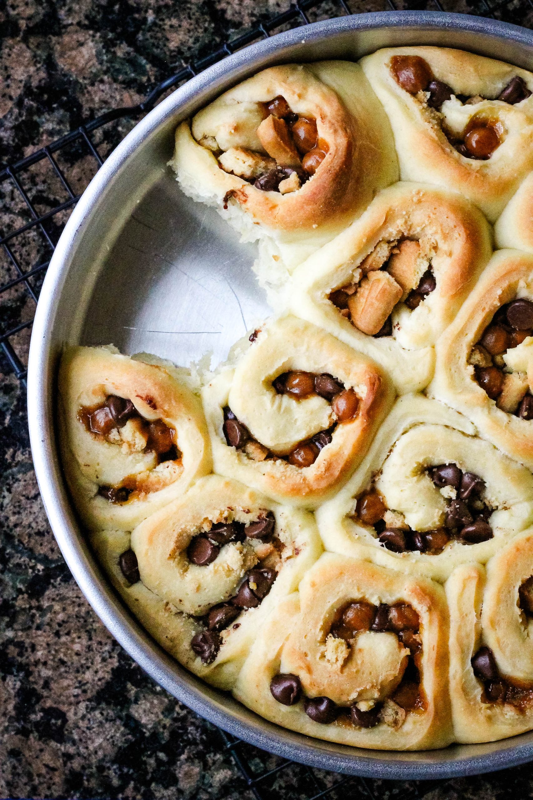 A pan of sweet rolls with Twix bars on top.