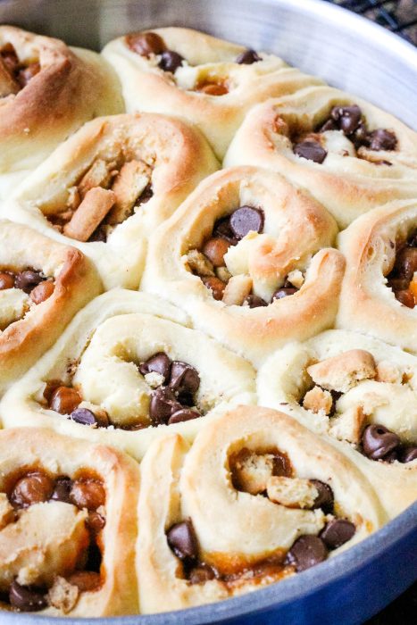 A pan with a cinnamon roll filled with chocolate chips and Twix bars.