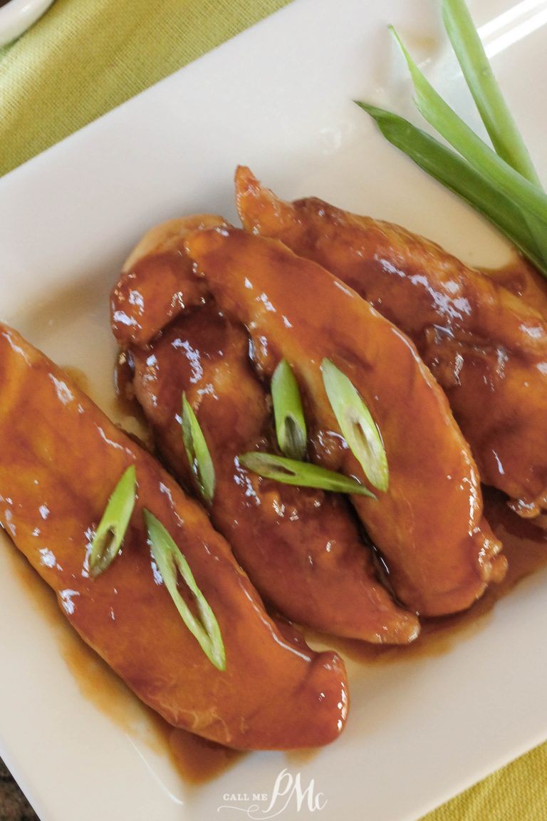 Three glazed chicken tenders, crafted from our Sticky Chicken Tenders Recipe and garnished with sliced green onions, are arranged on a white plate.