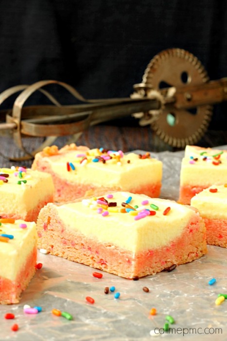 Dessert with colorful sprinkles rest on parchment paper, with an egg beater in the background.