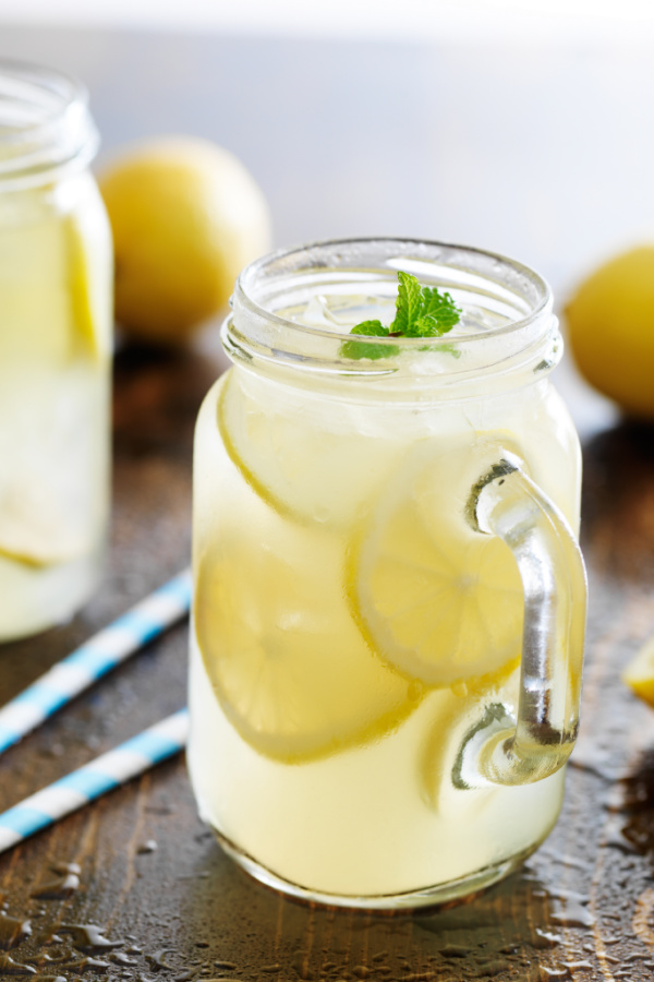 mason jar with handle full of lemonade, ice, lemon slices, and mint leaf Stoli Lemonade