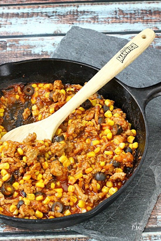 Sloppy Joe Wonton Cups Recipe Skillet with cooked ground meat, corn, black olives, and sauce, reminiscent of a Sloppy Joe Wonton Cups recipe, stirred with a wooden spoon.