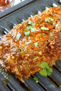 Close-up of a savory Mexican meatloaf recipe topped with chopped herbs, resting invitingly on a dark roasting pan.
