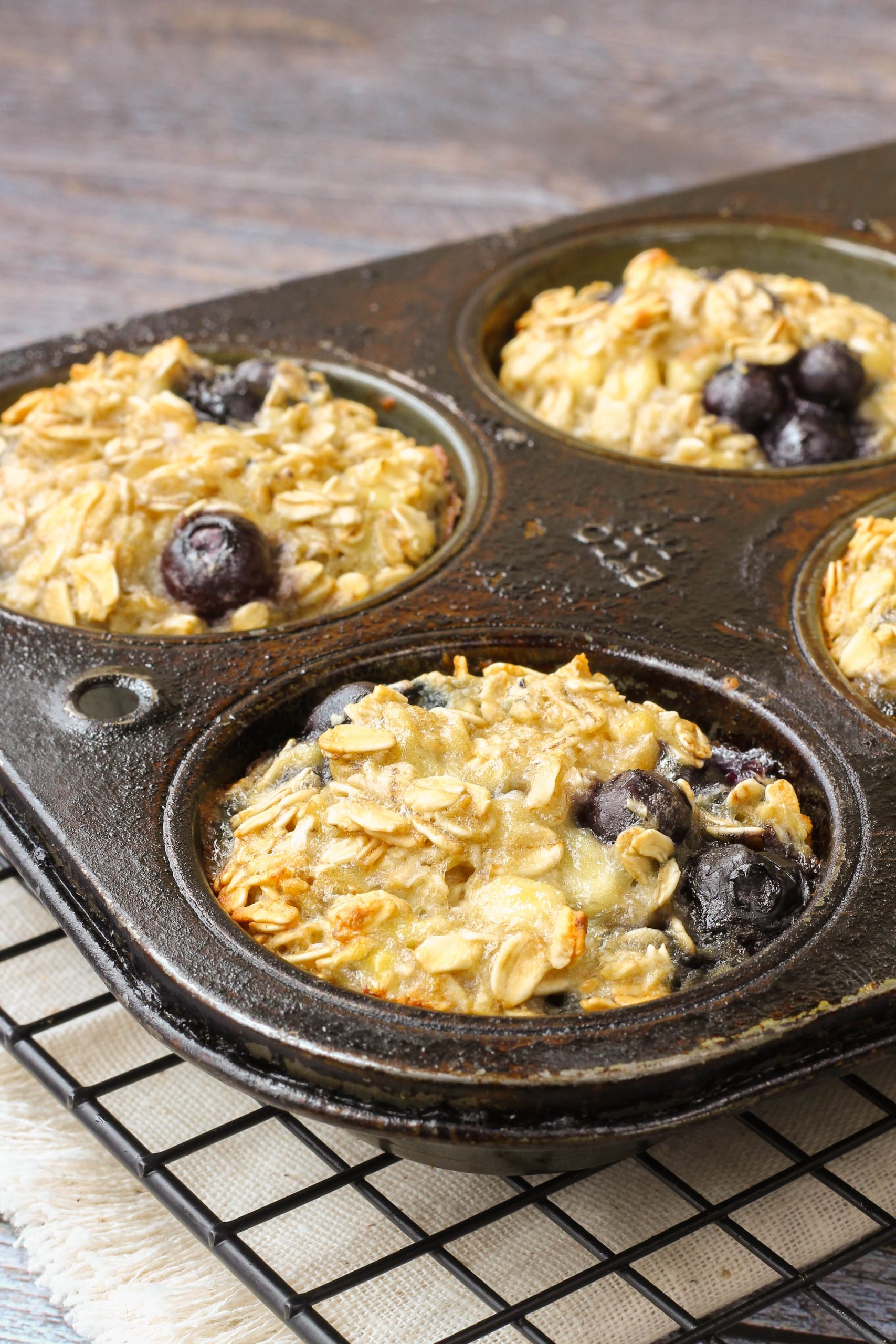 A close-up of muffins in a muffin tin, resting on a cooling rack.