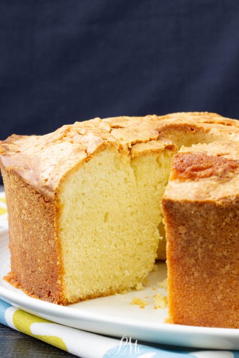 A round, golden-brown southern dessert with a slice removed, showing a dense, moist yellow interior on a white plate.