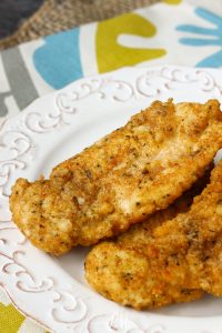 Two breaded and fried Copycat Chick-fil-a Chicken Strips served on a white decorative plate.