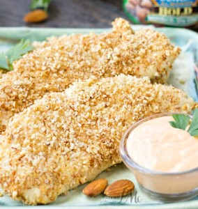almond crusted chicken tenders on a plate with dipping sauce.