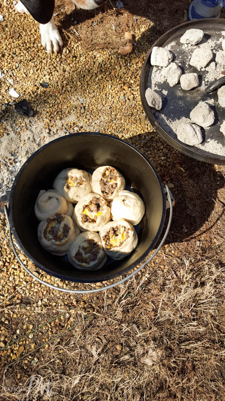 Dutch Oven Sausage Breakfast Pinwheels recipe Breakfast in Dutch oven next to a campfire.