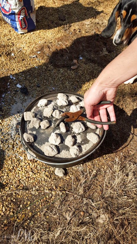Removing the lid from a campfire cast iron Dutch oven