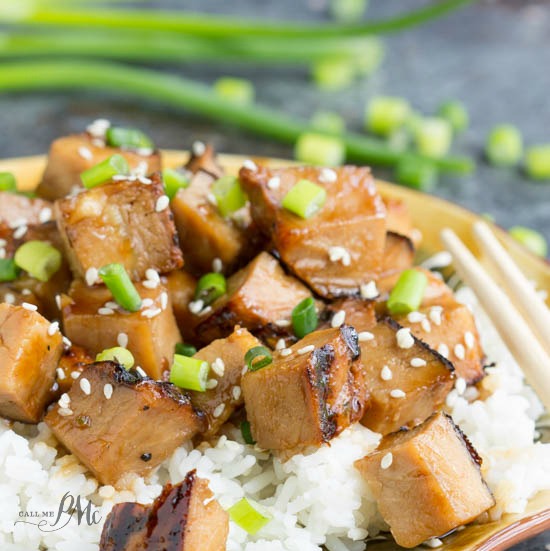 Cubes of meat over rice on a plate.