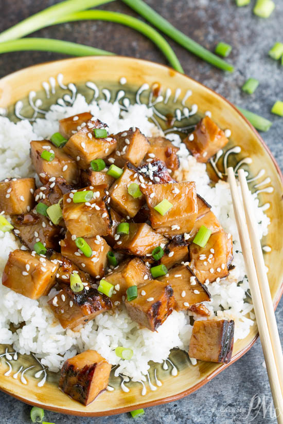 Cubes of meat over rice on a plate.