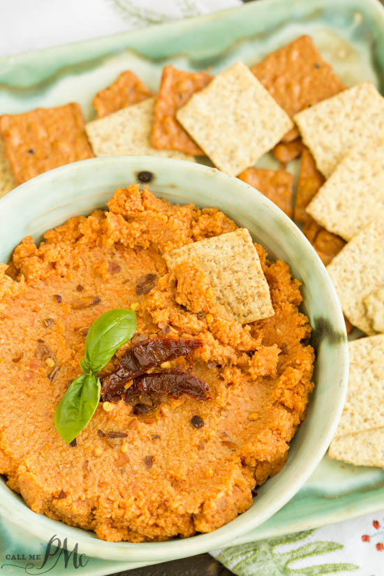 Sun Dried Tomato Hummus Recipe is creamy, spicy, and has a nice earthy flavor from the sun-dried tomatoes. This easy recipe comes together quickly and will become your go-to recipe! Reddish dip in a bowl.
